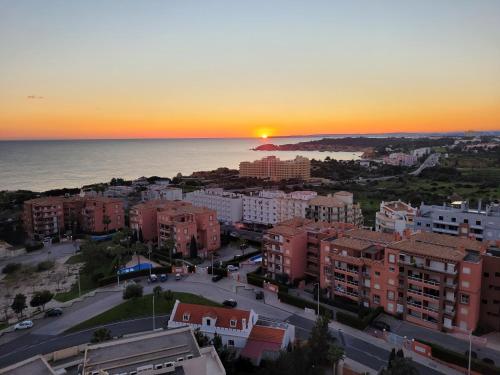 um pôr-do-sol sobre uma cidade com edifícios e o oceano em O WOW sunset beach and cliffs view em Portimão