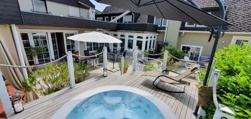 een buitenterras met een hot tub en een parasol bij Strandhaus an der Mosel in Valwig