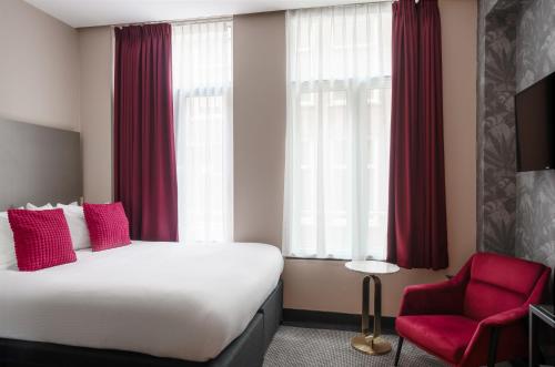 een hotelkamer met een bed en een rode stoel bij Krisotel in Amsterdam