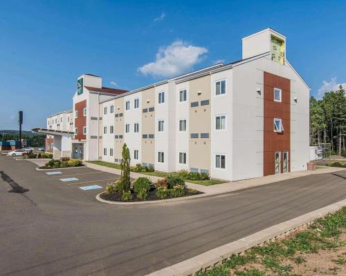 un grand bâtiment blanc avec un parking dans l'établissement Quality Inn, à Moncton