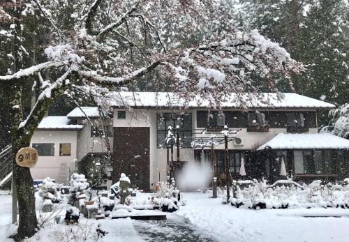 una casa coperta di neve di fronte di Pension Lanpou a Fujikawaguchiko