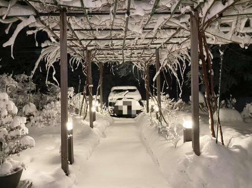 un'auto parcheggiata sotto un padiglione coperto di neve di Pension Lanpou a Fujikawaguchiko