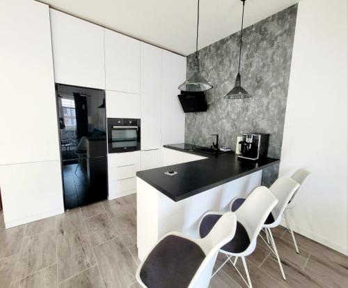 una cocina con armarios blancos y una encimera y sillas negras. en Apartament nad Jeziorem, en Olecko