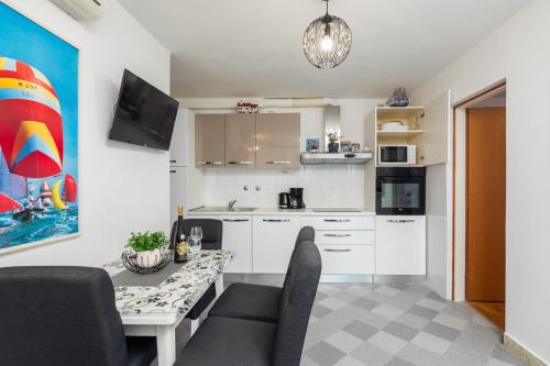 a kitchen with white cabinets and a table with chairs at Urban Edge - Beach Apartments in Omiš