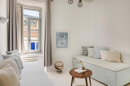 a white living room with a couch and a table at Hydra Hotel in Hydra