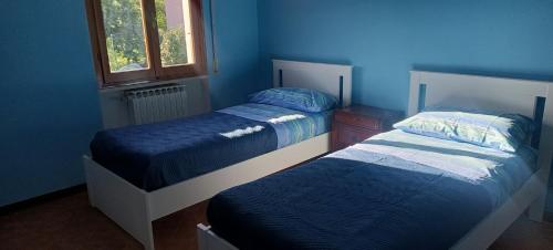 twee bedden in een kamer met blauwe muren bij Gian maria Vacanze in Altopascio