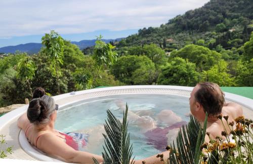 Ein Mann und eine Frau sitzen in einer Whirlpool-Badewanne in der Unterkunft Domaine de la Cascade Parfumée in Grasse