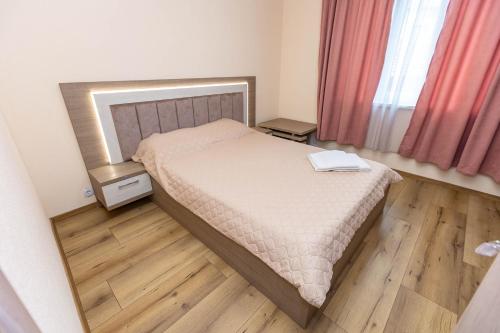 een kleine slaapkamer met een bed en een houten vloer bij Family Hotel Ambrozia in Sandanski