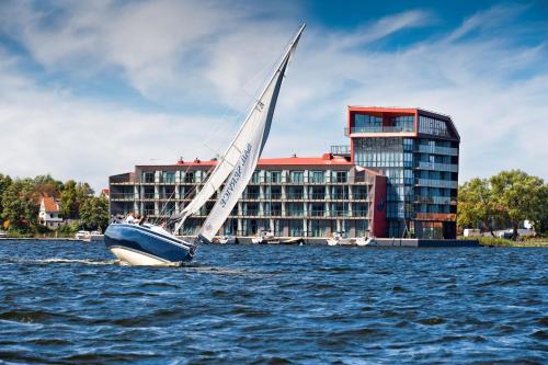 ein Segelboot im Wasser vor einem Gebäude in der Unterkunft Hotel Mikołajki Leisure & SPA - Destigo Hotels in Mikołajki