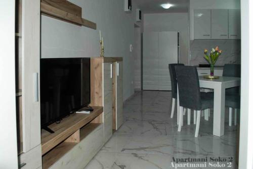 a living room with a television and a table with chairs at Apartman Soko 2 in Soko Banja