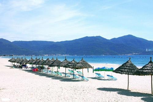 una fila de sombrillas y sillas en una playa en Lucia Beach Hotel, en Da Nang