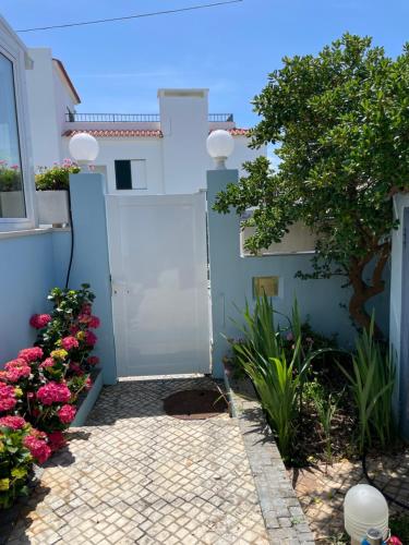 un jardin avec une porte et des fleurs devant une maison dans l'établissement Villa da Praia, à Sintra