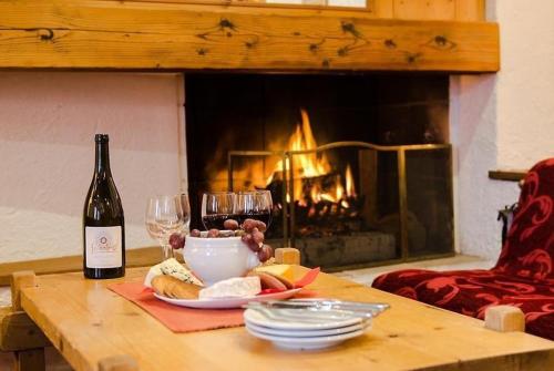 een tafel met een fles wijn en een bord eten en een open haard bij Rond Point d Arbois in Megève