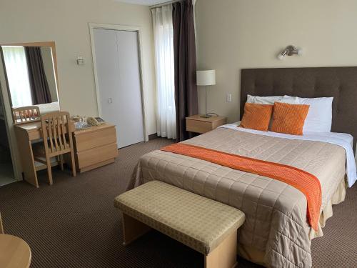 a hotel room with a large bed and a desk at Excelsior Hôtel Spa Sainte-Adèle in Sainte-Adèle