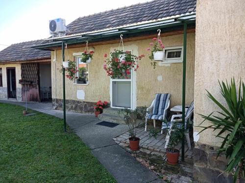 uma casa com um pátio com duas cadeiras e flores em Ágnes Vendégház Recsk em Recsk