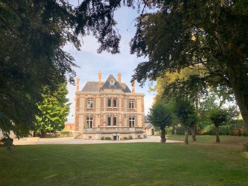 uma casa velha com um jardim relvado à frente. em Château de Ligny em Ligny-le-Châtel