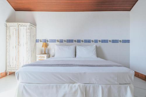 - une chambre avec un grand lit blanc et un plafond en bois dans l'établissement Pousada Porto Fino, à Cabo Frio