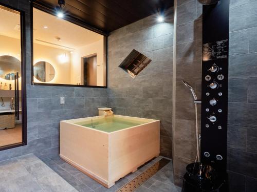 KONJAKUSO Nara Naramachi "MUSHIBUROYA" Sauna Villa في نارا: حمام مع حوض استحمام ودش