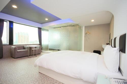 a bedroom with a large white bed and a bathroom at 幸福星空時尚旅館 in Luodong