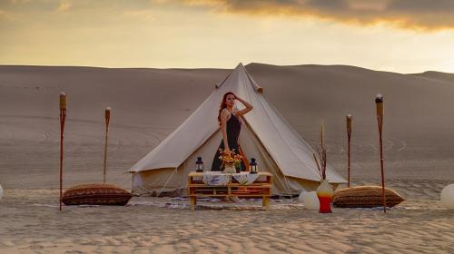 una mujer parada dentro de una tienda en el desierto en Duna Camp Huacachina, en Ica