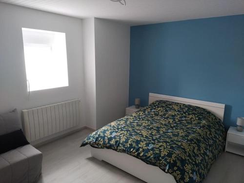 - une chambre avec un lit et un mur bleu dans l'établissement Gîte des deux petits doudous, à Colombey-les-Deux-Églises