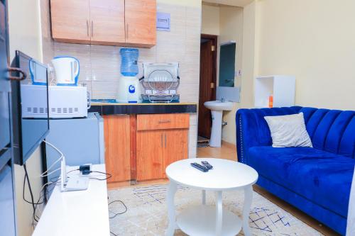 a living room with a blue couch and a table at Sunlit Furnished Studio, Kisii in Kisii