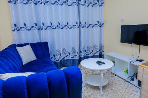 a living room with a blue couch and a table at Sunlit Furnished Studio, Kisii in Kisii