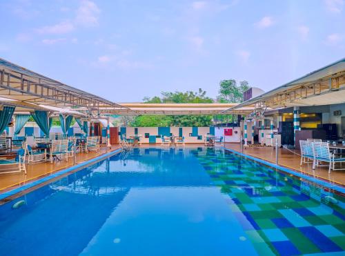 una gran piscina con sillas y mesas en Sayaji Pune, en Pune