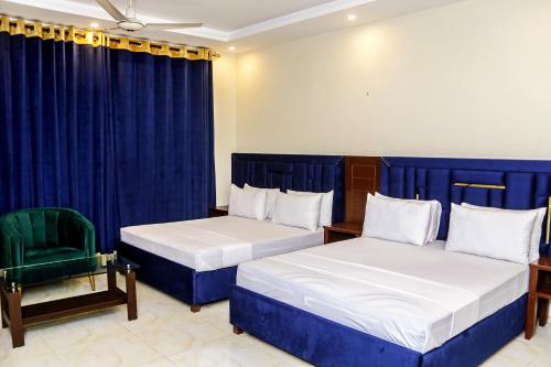 1 dormitorio con 2 camas y silla verde en Royalton INN Liberty, en Lahore