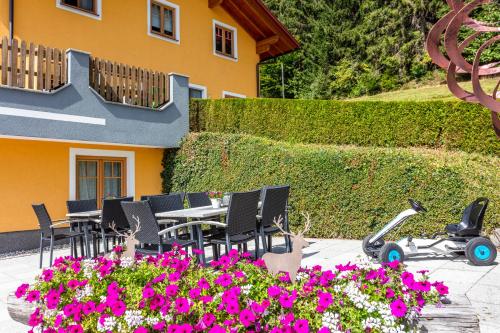 um pátio com uma mesa, cadeiras e flores em Landhaus Hochkönig em Mühlbach am Hochkönig