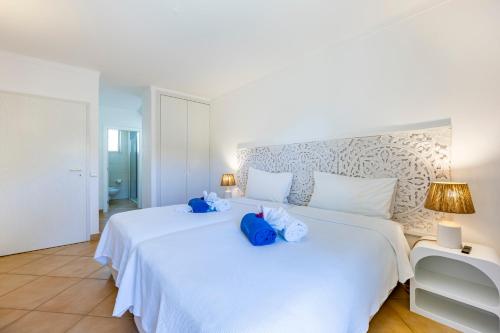 una camera da letto con un letto bianco con animali di peluche blu di Vila Palmeira Beach Resort a Lagos