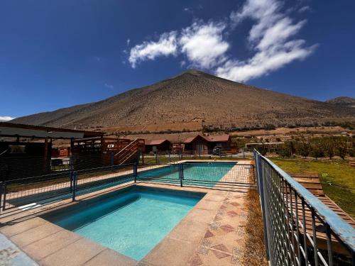 a swimming pool with a mountain in the background at Cabañas Vicuña Cielo de Peralillo - Valle de Elqui in Vicuña