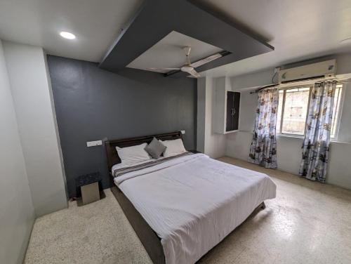 1 dormitorio con 1 cama grande con sábanas blancas en Swanky Sojourns Cosy Home Stay, en Kolhapur