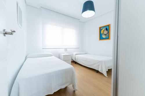 een witte kamer met een bed en een spiegel bij luminoso apartamento en maliaño in Maliaño