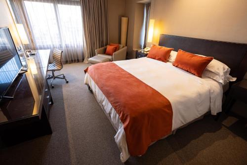 um quarto de hotel com uma cama grande com almofadas laranja em Libertador Hotel em Buenos Aires