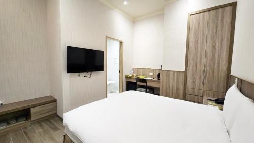 una camera d'albergo con letto bianco e TV di Grace Hotel Dunbei a Taipei