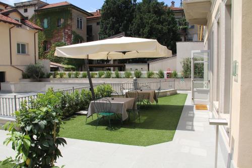 un patio con mesa y sombrilla en Hotel Di Varese, en Varese