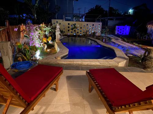 a swimming pool with two benches in front of a building at Villa NiMo Jimbaran in Jimbaran