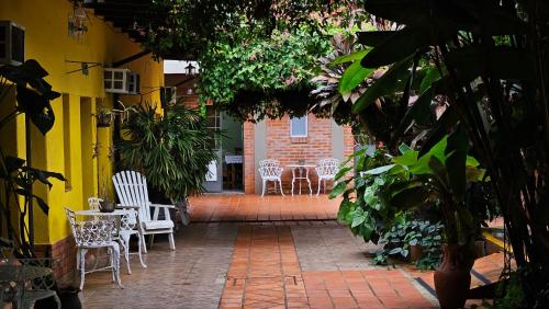 un patio avec des chaises blanches, des tables et des plantes dans l'établissement Iguazu Hojas Verdes, à Puerto Iguazú