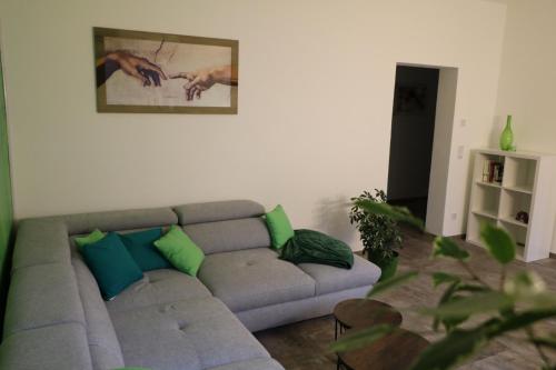 ein Wohnzimmer mit einem grauen Sofa und grünen Kissen in der Unterkunft Pasithea Zittau in Zittau