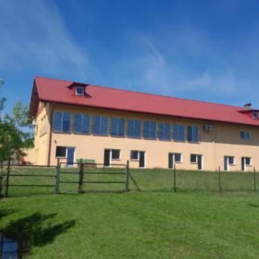 duży budynek z czerwonym dachem na polu w obiekcie Pokoje gościnne Trąbki Małe k.Gdańska w mieście Trąbki Małe