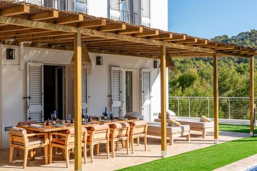 eine hölzerne Pergola auf einer Terrasse mit einem Tisch und Stühlen in der Unterkunft Cap Martinet Talamanca Vila Can Tashellu, Boutique 5 bed - Sea and Forest View in Talamanca