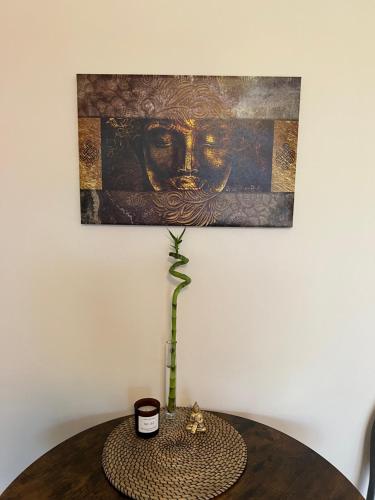 une table avec une plante et une peinture sur le mur dans l'établissement Ferienwohnung Aspelohe - Apartment 2, à Norderstedt