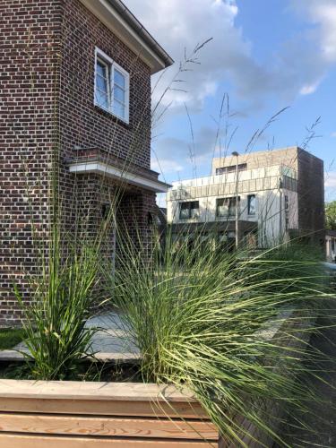 un bâtiment en briques avec de l'herbe haute devant lui dans l'établissement Hotel Insel Pension, à Niebüll