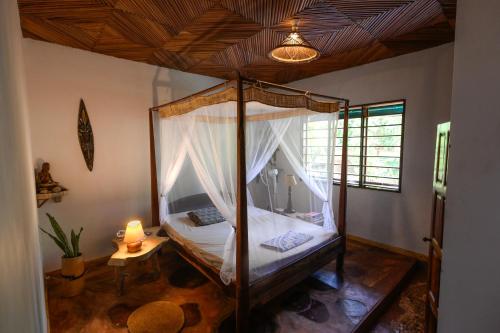 AmbolobozoShambala Madagascar: Beachfront Lodge And Adventures的一间卧室,卧室内配有一张天蓬床