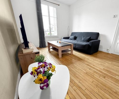 ein Wohnzimmer mit einem Sofa und einem Tisch mit Blumen darauf in der Unterkunft Élégant Pied-à-Terre à Beauvais in Beauvais