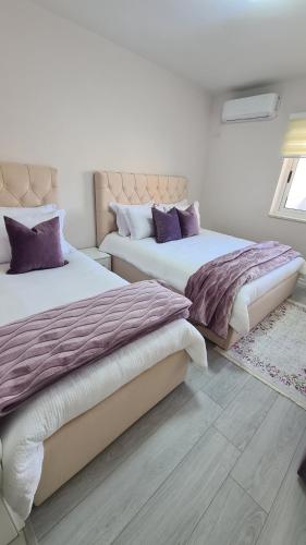 two beds in a bedroom with purple pillows at Dei Cozy Apartment in Shkodër