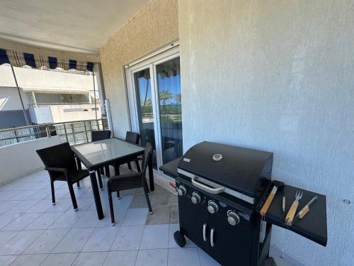 a barbecue grill on a balcony with a table and chairs at Luxury Sea View Apartment in Vlorë