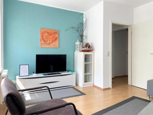 een woonkamer met een flatscreen-tv aan een blauwe muur bij Gemütliches Apartment, Seenähe, WM, WLAN, Balkon in Markkleeberg