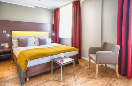 ein Hotelzimmer mit einem Bett und einem Stuhl in der Unterkunft Leonardo Hotel München City Center in München